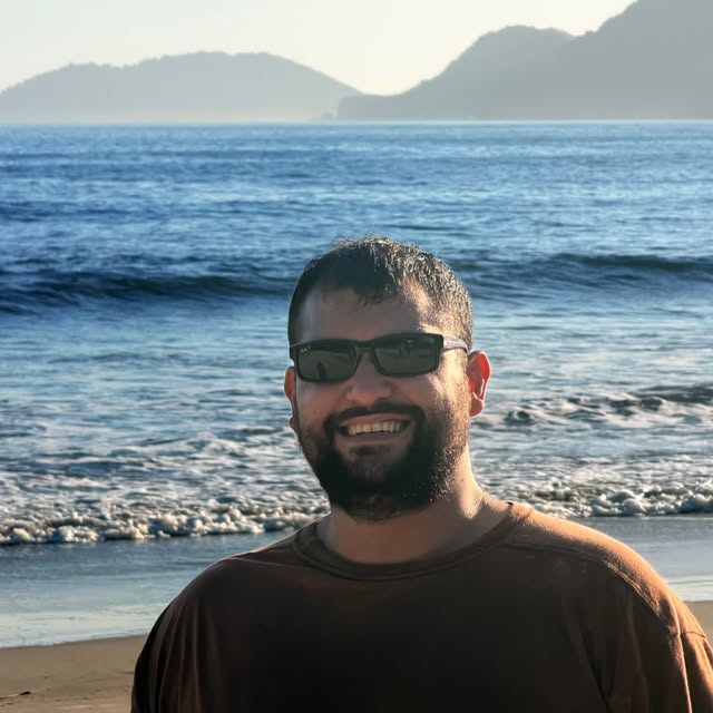 LeaoMC de óculos escuros à beira-mar